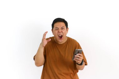 Kızgın bir Asyalı bağırıyor ve beyaz bir arka planda cep telefonu ekranını işaret ediyor..