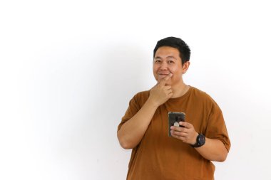 Asyalı bir erkek, akıllı telefon kullanırken kazanan bir hareketle tepki veriyor ve yüz ifadesi heyecanlanıyor..