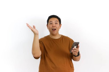 Asyalı bir erkek, akıllı telefon kullanırken kazanan bir hareketle tepki veriyor ve yüz ifadesi heyecanlanıyor..