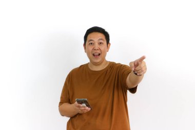 Asyalı bir erkek, akıllı telefon kullanırken kazanan bir hareketle tepki veriyor ve yüz ifadesi heyecanlanıyor..