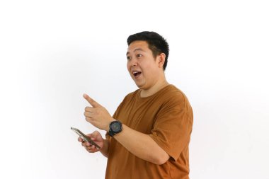 Asyalı bir erkek, akıllı telefon kullanırken kazanan bir hareketle tepki veriyor ve yüz ifadesi heyecanlanıyor..