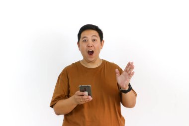 Asyalı bir erkek, akıllı telefon kullanırken kazanan bir hareketle tepki veriyor ve yüz ifadesi heyecanlanıyor..