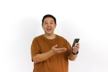 Asyalı bir erkek, akıllı telefon kullanırken kazanan bir hareketle tepki veriyor ve yüz ifadesi heyecanlanıyor..