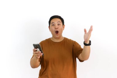 Endonezyalı bir Asyalı beyaz arka planda akıllı telefonunu tutarken avucunun içine bağırıyor..