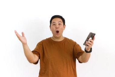 Endonezyalı bir Asyalı beyaz arka planda akıllı telefonunu tutarken avucunun içine bağırıyor..