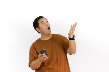 Endonezyalı bir Asyalı beyaz arka planda akıllı telefonunu tutarken avucunun içine bağırıyor..