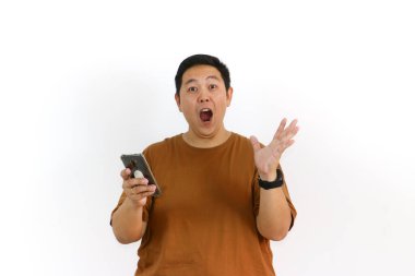 Endonezyalı bir Asyalı beyaz arka planda akıllı telefonunu tutarken avucunun içine bağırıyor..