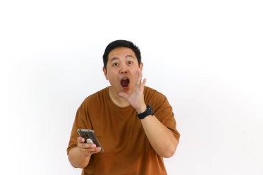 Endonezyalı bir Asyalı beyaz arka planda akıllı telefonunu tutarken avucunun içine bağırıyor..