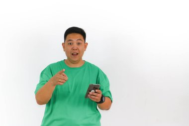 Açık ağızlı ve geniş gözlü Asyalı bir adam boş bir alan gösteriyor, muhtemelen yeni bir ürün ya da fikri telefonla sunuyor..