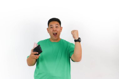 Mutlu Asyalı adam elinde Endonezya parası dolu siyah bir cüzdan tutuyor, kameraya neşeyle gülümsüyor..