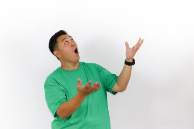 Şok olmuş, koyu saçlı, yeşil gömlekli ve siyah saati beyaz arka planda şaşkınlığını ifade eden bir adamın ayrı bir stüdyo çekimi..