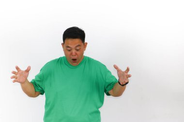 Şok olmuş, koyu saçlı, yeşil gömlekli ve siyah saati beyaz arka planda şaşkınlığını ifade eden bir adamın ayrı bir stüdyo çekimi..