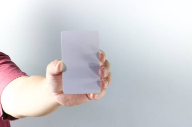 Bir adamın sol elinin yakın plan resmi boş, düz dikdörtgen kağıt bir kartı nazikçe kavraması, metin kaplaması ya da grafik tasarım modellemeleri için mükemmel.