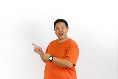 40 'lı yaşlarda turuncu bir tişört giyen yakışıklı bir erkek manken. Sağ taraftaki büyük beyaz boşluğu işaret ediyor. Mesajınız ya da logonuz için mükemmel..