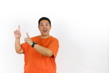 Mutlu adam stüdyo ortamında poz veriyor, boş alana doğru hareket ediyor, büyük bir ürün tanıtımı, özel promosyon, duyuru veya potansiyel müşteriler için yeni bir fırsat öneriyor..