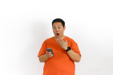 Turuncu tişörtlü, akıllı telefonlu, ağzı açık Asyalı bir adam el kaldırdı ve şok etkisi yarattı..