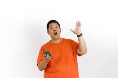 Turuncu tişörtlü, akıllı telefonlu, ağzı açık Asyalı bir adam el kaldırdı ve şok etkisi yarattı..
