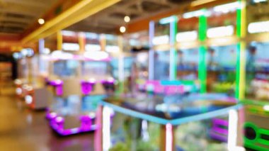 Kalabalık bir oyun salonunun arka planında canlı pençe makineleri, eğlenceli bir atmosfer ve gece hareketli bir ortam yaratıyor..