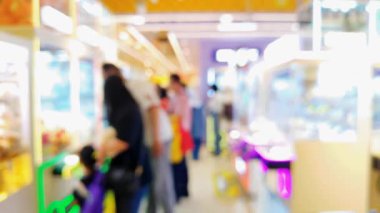 Kalabalık bir oyun salonunun arka planında canlı pençe makineleri, eğlenceli bir atmosfer ve gece hareketli bir ortam yaratıyor..