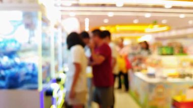 Işıl ışıl ışıkları olan kalabalık eğlence merkezinin bulanık arka planı ve pençe makinelerinden ödül kazanmaya çalışan insanlar..