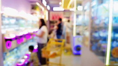 Canlı bir oyun salonunun içini ön plan pençe makineleri ve sıcak, parlak ışıklarla bulanıklaştırdı..