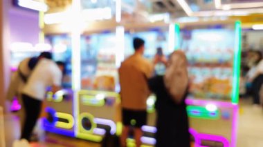 Canlı bir oyun salonunun içini ön plan pençe makineleri ve sıcak, parlak ışıklarla bulanıklaştırdı..