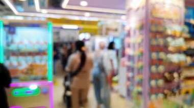 Canlı bir oyun salonunun içini ön plan pençe makineleri ve sıcak, parlak ışıklarla bulanıklaştırdı..