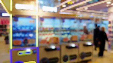 Canlı bir oyun salonunun içini ön plan pençe makineleri ve sıcak, parlak ışıklarla bulanıklaştırdı..