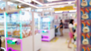 Renkli pençe makine oyunlarının bulanık arka planında insanlar şanslarını denerken şehir ortamında rahat bir atmosferin tadını çıkarıyorlar..