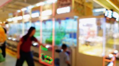 Renkli pençe makine oyunlarının bulanık arka planında insanlar şanslarını denerken şehir ortamında rahat bir atmosferin tadını çıkarıyorlar..