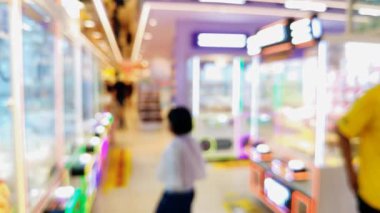 Renkli pençe makine oyunlarının bulanık arka planında insanlar şanslarını denerken şehir ortamında rahat bir atmosferin tadını çıkarıyorlar..