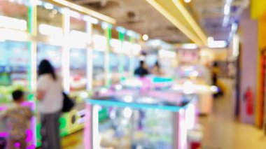 Renkli pençe makine oyunlarının bulanık arka planında insanlar şanslarını denerken şehir ortamında rahat bir atmosferin tadını çıkarıyorlar..