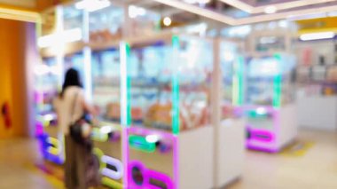 Renkli pençe makine oyunlarının bulanık arka planında insanlar şanslarını denerken şehir ortamında rahat bir atmosferin tadını çıkarıyorlar..