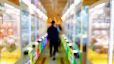 Renkli pençe makine oyunlarının bulanık arka planında insanlar şanslarını denerken şehir ortamında rahat bir atmosferin tadını çıkarıyorlar..