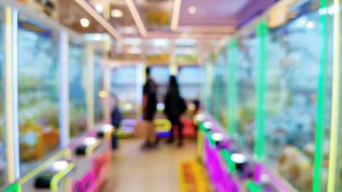 Renkli pençe makine oyunlarının bulanık arka planında insanlar şanslarını denerken şehir ortamında rahat bir atmosferin tadını çıkarıyorlar..