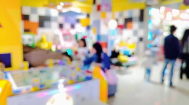 Canlı bir eğlence merkezinde renkli oyunlar ve kalabalıklarla dolu hareketli oyun sahnesinin bulanık arkaplanı.