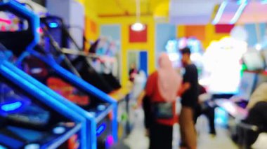 Etkileşimli oyun istasyonu atari salonundan hoşlanan insanlarla dolu hareketli bir oyun odasının bulanık görünümü, renkli görüntüler.