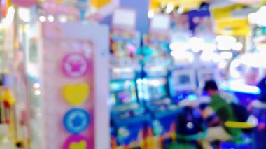 Etkileşimli oyun istasyonu atari salonundan hoşlanan insanlarla dolu hareketli bir oyun odasının bulanık görünümü, renkli görüntüler.