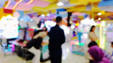 Etkileşimli oyun istasyonu atari salonundan hoşlanan insanlarla dolu hareketli bir oyun odasının bulanık görünümü, renkli görüntüler.