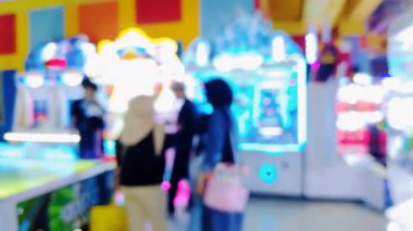 İnsanların bulanık arkaplanı, çağdaş bir eğlence merkezinde oyun istasyonu eğlence faaliyetlerine katılıyor.