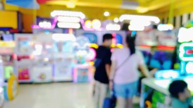 Etkileşimli oyun istasyonu atari salonundan hoşlanan insanlarla dolu hareketli bir oyun odasının bulanık görünümü, renkli görüntüler.