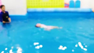 Kendini adamış bir eğitmenle kapalı bir havuzda yüzmeyi öğrenen çocukların bulanıklığı..