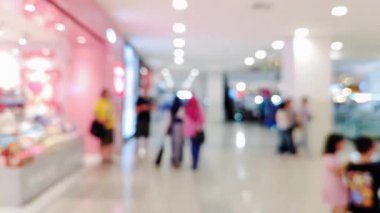 Ailesiyle yürüyen ve perakende satış mağazasının ışıklarını dağıtan insanların olduğu soyut alışveriş merkezi sahnesi.