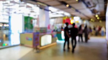 Akrabalarıyla yürüyen ve reklam projesi için ışık saçan insanların bulanıklığını gösteren yoğun bir mağaza.