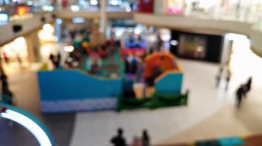 Akrabalarıyla yürüyen ve reklam projesi için ışık saçan insanların bulanıklığını gösteren yoğun bir mağaza.