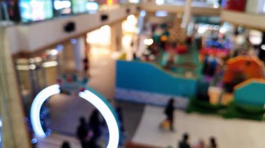 Akrabalarıyla yürüyen ve reklam projesi için ışık saçan insanların bulanıklığını gösteren yoğun bir mağaza.