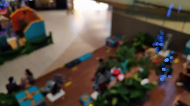 Akrabalarıyla yürüyen ve reklam projesi için ışık saçan insanların bulanıklığını gösteren yoğun bir mağaza.