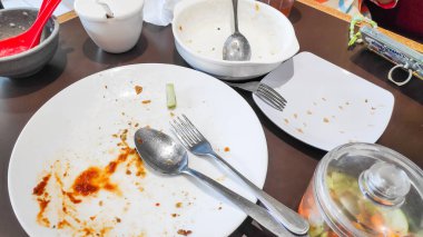 Ahşap bir masada çeşitli kirli tabaklar ve kahvaltıdan arta kalan yemekler..