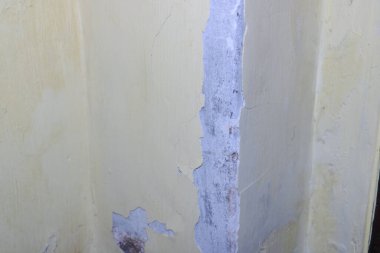 Eski desenli bir duvar yüzeyindeki soyulma şekillerini gösteren yakın plan bir fotoğraf..
