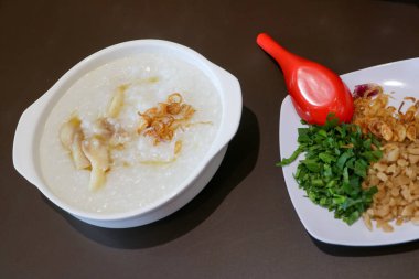 Dilimlenmiş kereviz yaprağı, kızarmış hamur köftesi ve kızarmış arpacık soğanı gibi beyaz bir tabakta servis edilen yulaf lapası malzemelerinin yakın çekim fotoğrafını çek.